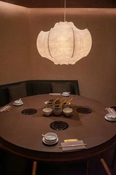 Warm lantern hangs above round dining table Stock Photos