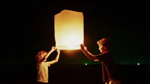 Warm Lantern Light Shines As Boys Release It Into The Sky Stock Footage 305507691