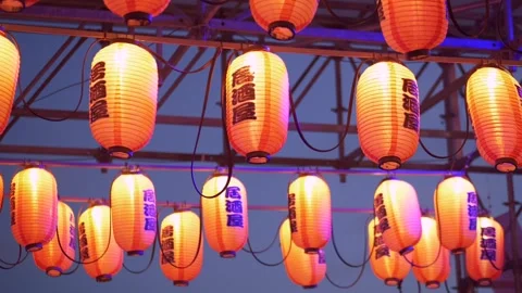 Warm lantern lights glowing at evening outdoor festival, soft crowd blur and Stock Footage 321817146