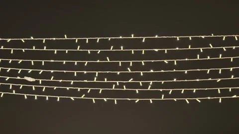 Warm led string lights creating rows of glowing decoration on dark background Stock Footage 335885595
