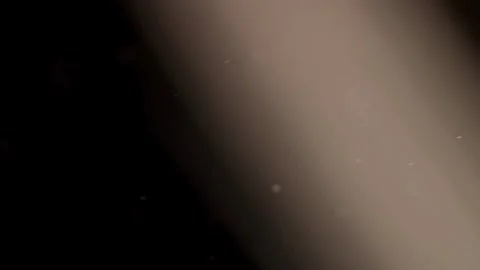 Warm light beam illuminates floating dust in dark room Stock Footage 329598391