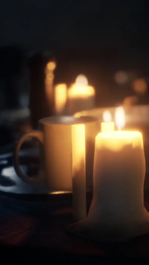 Warm light from candles and cup set on wooden table at night Stock Footage 338427113