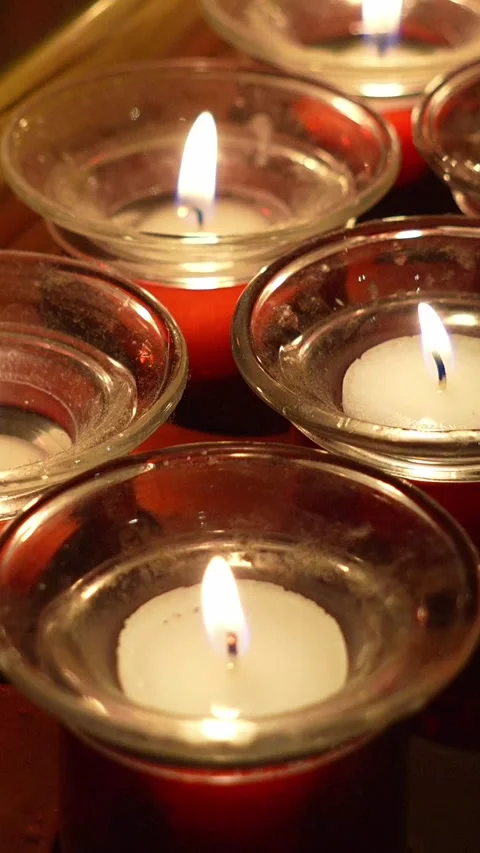 Warm light emanates from numerous votive candles burning in glass holders 库存影片 311462500