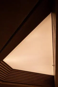 Warm light glows through triangular ceiling opening Stock Photos