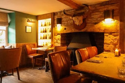 Warm light illuminating a rustic cozy restaurant interior with stone firepl.. Stock Photos