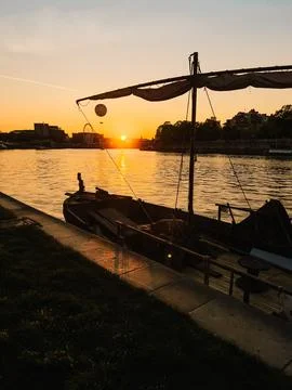 Warm light of setting sun illuminates an old wooden boat moored, with Ferris Stock Photos