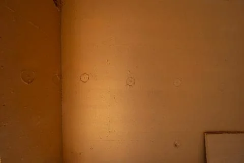 Warm light on unfinished plaster wall with circular anchor marks Stock Photos