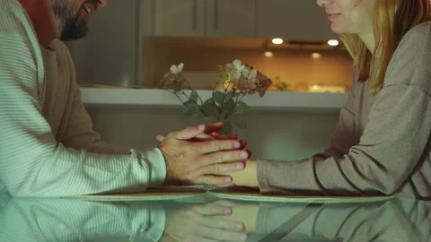 Warm lighting illuminates a couple holding hands across a glass table, find.. Stock Footage 304053159