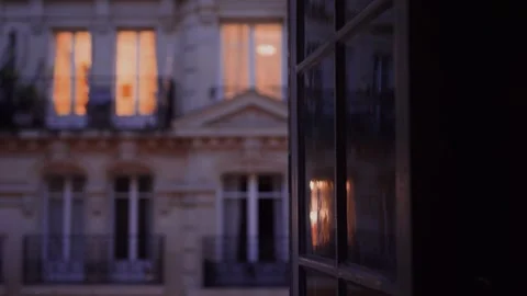 Warm lights reflecting on a window in a parisian building at dusk Stock Footage 306582020