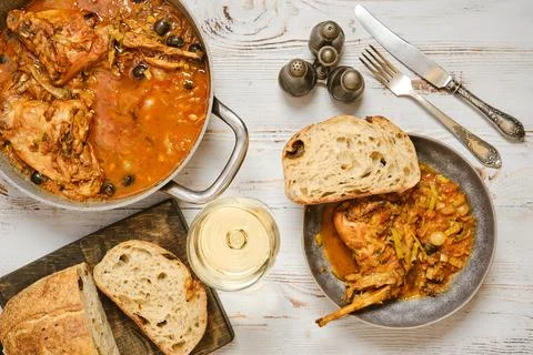 Warm meal with rabbit stew, bread, and white wine on a wooden table Stock Photos