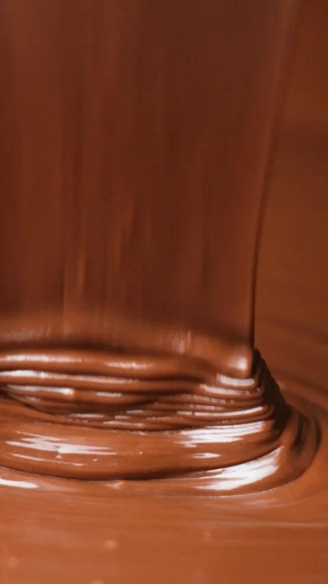 Warm melted chocolate streaming down and stacking in slow motion vertical orient Stock-Footage 344873077