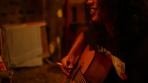Warm, mid shot of a man with long curly hair playing guitar 스톡 동영상 71832974