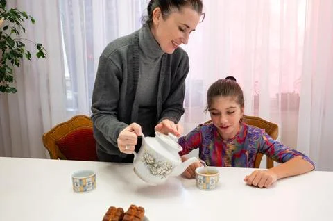 Warm moments shared over tea as a mother serves her daughter in a cozy home.. Stock-Fotos