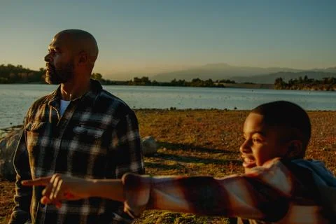 Warm moody image of 8 year-old son at the lake excitedly pointing at something Stock Photos