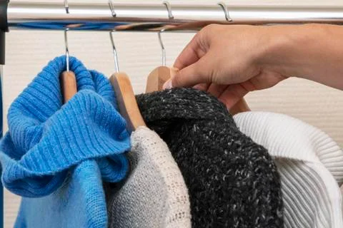 Warm multi-colored knitted sweaters hang on wooden trempels Stockfoto's