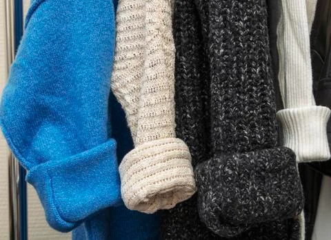 Warm multi-colored knitted sweaters hang on wooden trempels Foto stock