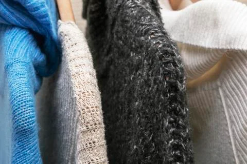 Warm multi-colored knitted sweaters hang on wooden trempels Stock Photos
