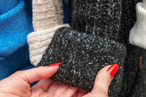Warm multi-colored knitted sweaters hang on wooden trempels Stock Photos