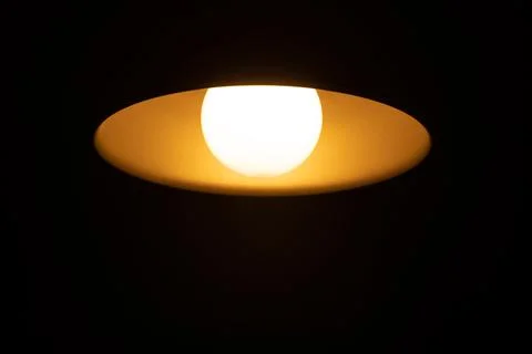 Warm orange LED lamp in the ceiling on a dark background Stock Photos