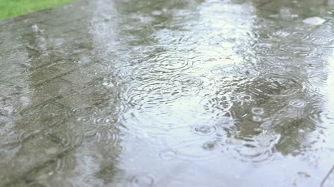 Warm rain drops and splashes hit the tile sidewalk in the street. close-up view Video stock 158071009