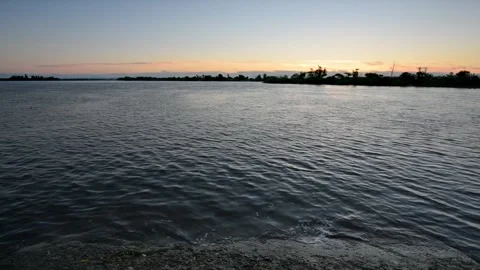 Warm river sunset and gentle waves crashing on pier Stock Footage 155200489