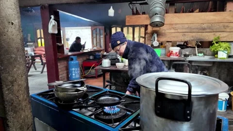 Warm rustic kitchen stove with boiling pots preparing breakfast in a cozy Stock Footage 335919646