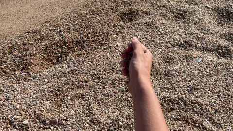 Warm sand running through fingers with seascape background Stock-Footage 277611245