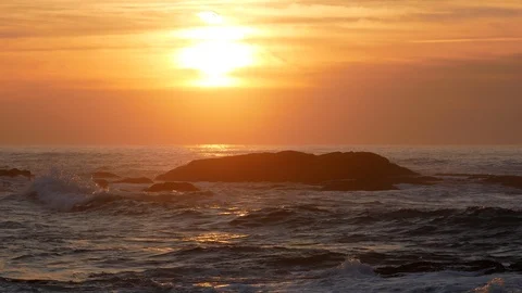 Warm soft light at sunset over ocean with waves splashing on rocks Stock Footage 103063230