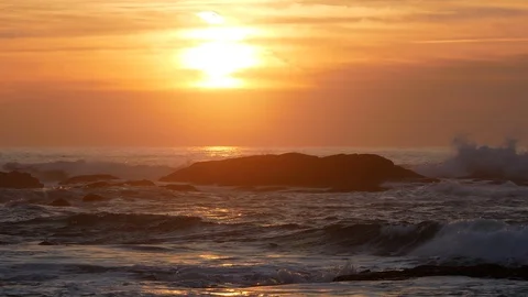 Warm soft light at sunset over ocean with big waves splashing on rocks Stock Footage 103065034