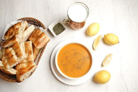 Warm soup and bread served with lemon on a simple table Stock Photos