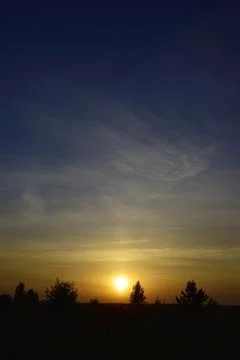 Warm spring sunset. The sun sets in light cirrus clouds Stock Photos