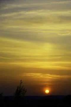 Warm spring sunset. The sun sets in light cirrus clouds Stock Photos