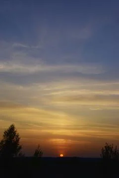 Warm spring sunset. The sun sets in light cirrus clouds Stock Photos