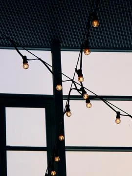 Warm string lights against window grid Stock Photos