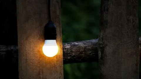 Warm string lights draped over a classic wooden fence, evoking a cozy and n.. Stock Photos