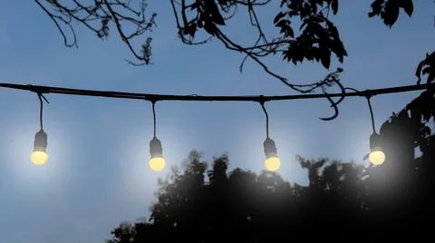 Warm string lights draped over a classic wooden fence, evoking a cozy and n.. Stock Photos