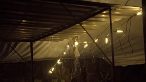 Warm String Lights Hanging Under Covered Patio on Rainy Night Close Up View Stock Footage 339763643
