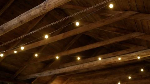 Warm string lights illuminating rustic wooden ceiling Stock Photos
