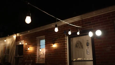 Warm string lights outside brick house at night 動画素材 337728867