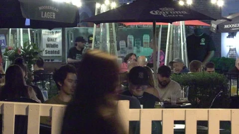 Warm summer night with people walking and restaurant patios open in new normal Vidéo 155583855