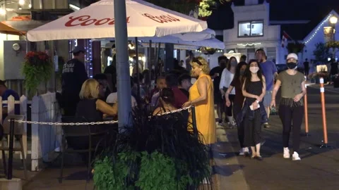 Warm summer night with people walking and restaurant patios open in new normal Vidéo 155584640