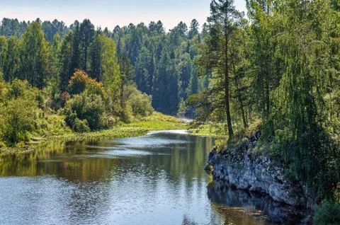 Warm summer river flows in the middle of rocks and green forest 写真素材