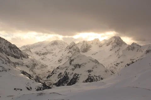 Warm sun rays breake through winter clouds. Alps mountains. Stock Photos