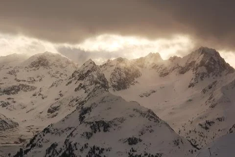 Warm sun rays breake through winter clouds. Alps mountains. Foto stock