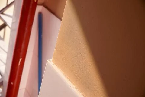 Warm sunlight casting shadows on a textured beige wall Stock Photos