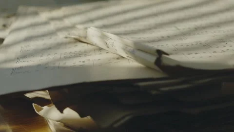 Warm sunlight casts striped shadows across torn vintage sheet music as the Stock Footage 346800087