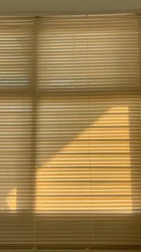 Warm sunlight forms a bold geometric pattern across closed horizontal windo.. Stock Photos