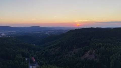 Warm sunset glow spreads across layered pine hills, tree-filled valley, and Stock Footage 345170836