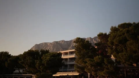 Warm sunset light illuminates mountain peaks above a peaceful resort town Stock Footage 341556758