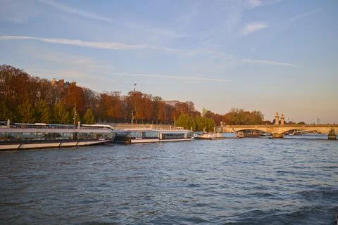 Warm sunset light over the Seine River with boats docked along the riverside Stock Photos